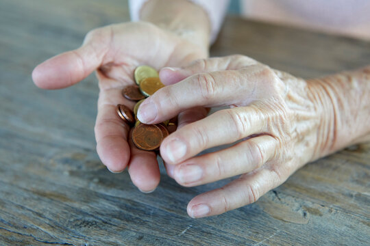 Hands of senior woman counting coins at table