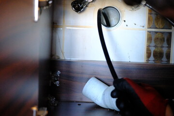 A plumber is trying to open a clogged bathroom pipe using a camera system. Close-up view of opening...