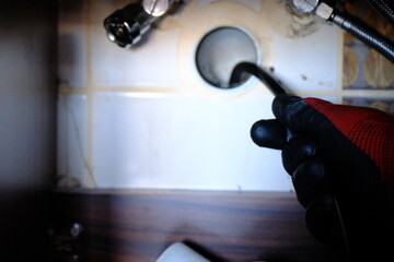 A plumber is trying to open a clogged bathroom pipe using a camera system. Close-up view of opening...