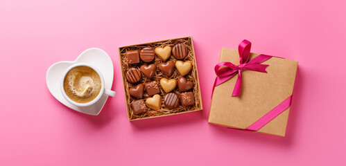 A romantic Valentines Day setup featuring a box of assorted chocolates and a steaming cup of coffee