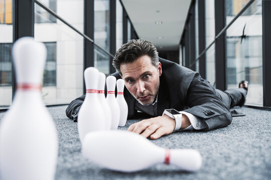Diligent manager lying on the floor in office passageway with pins