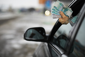 Hand Holding Russian Rubles Out of Car Window on Snowy Day - Financial Transactions