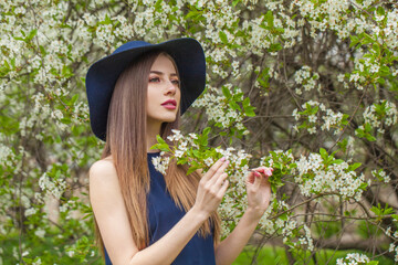 Gorgeous young woman with natural make-up and long smooth straight hair posing in spring flower garden park