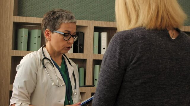Portrait of empathetic nature female doctor in uniform telling bad news about health status, giving support and consoling upset sick middle aged woman patient at hospital.