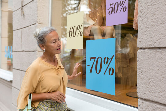 Senior woman looking in shop window of a boutique
