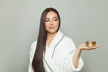 Cheerful brunette woman showing a cream tube box in her palm hand on white background