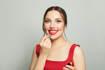 Happy emotional woman with bright make-up applying red lipstick, portrait