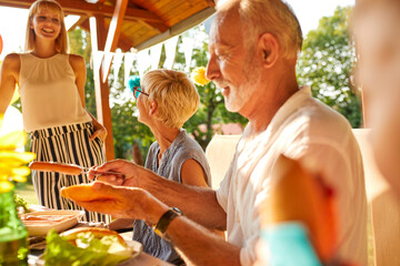 Senior man preparing a hot dog on a garden party