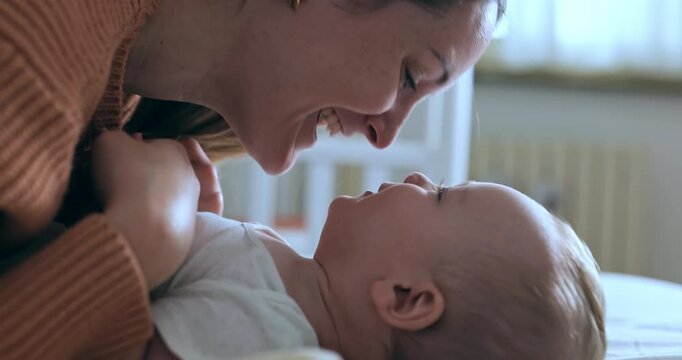 Super slow motion of happy smiling mother and newborn baby son having fun to play together with mother in nursery in morning. Parenthood, childcare, life, maternity, motherhood
