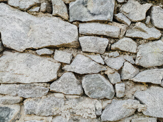 Stacked light granite stone brick wall surface. Close-up of a beautifully folded granite stone fence, showcasing the natural texture and elegance of the granite stones.