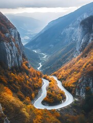 A photo of a winding mountain road, lined with vibrant autumn foliage and overlooking a deep valley.