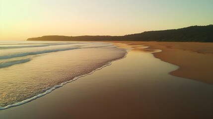 Obraz premium A photo of a tranquil beach at sunrise, with gentle waves washing over smooth, golden sand.