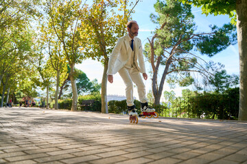 Man roller skating in a sunny park surrounded by trees
