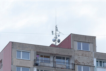 A very large apartment building prominently featuring a satellite dish securely mounted on its...