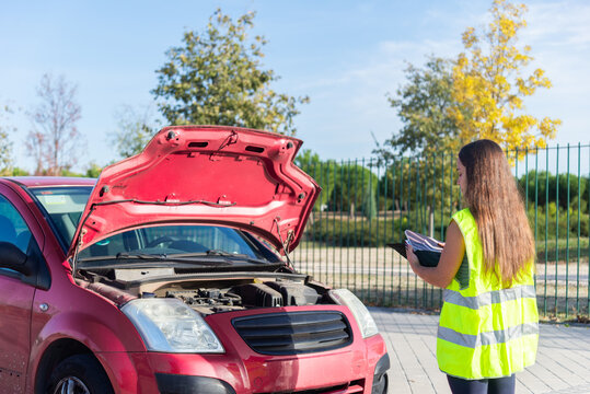 Female insurance agent assessing car accident damage outdoors
