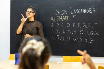 Sign language class with teacher and alphabet lesson on chalkboard