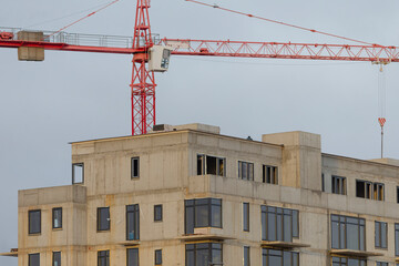 A large and impressive building is currently under construction, featuring a towering crane in the background overseeing the work being done