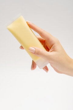 Anonymous hand holding a yellow facial mask tube with focus on product