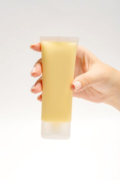 Anonymous hand holding a yellow face mask tube for skincare