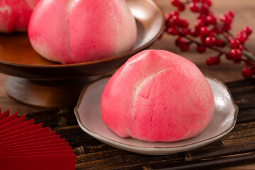 Pink Chinese peach birthday bun food shoutao on wooden table background.