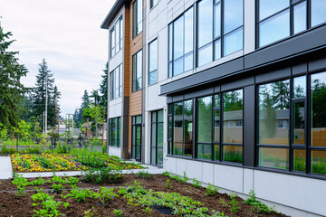 Affordable apartment building, clean and minimal exterior with large windows and a community garden