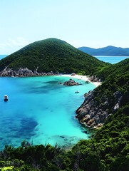 Fototapeta premium A photo of a remote island with lush green cliffs, surrounded by turquoise waters and small white sand beaches.