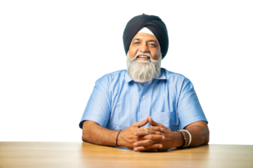 Senior Sikh man sitting at table with white background, expressing various emotions and gestures
