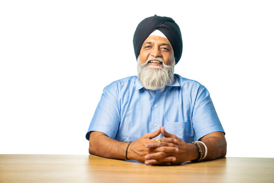 Senior Sikh man sitting at table with white background, expressing various emotions and gestures