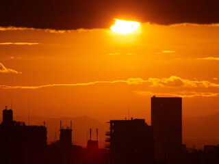 Fototapeta premium 鮮やかな夕焼けと夕日の風景と都市の高層ビルの景色