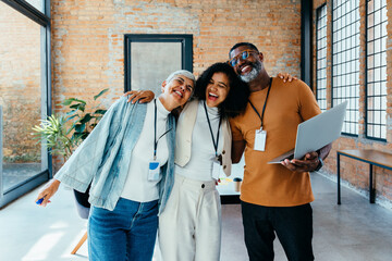 Colleagues sharing a joyful moment in an airy office space with brick walls and natural light