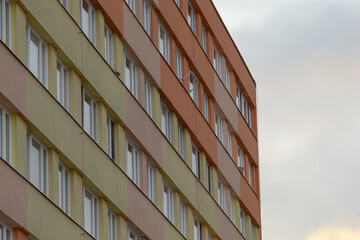 An impressive building featuring numerous windows, set against a backdrop of an overcast cloudy sky that adds to its charm