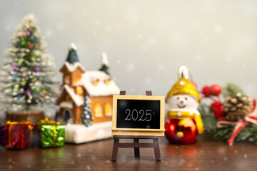 Easel with text Year 2025. Xmas winter holiday. Decoration, celebration. The concept of the beginning of the new year. Christmas tree, gifts and a house with snowfall