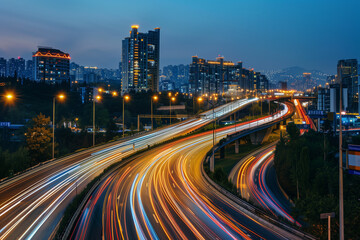 Fototapeta premium Streaks of moving car lights against the backdrop of city lights at night