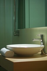Fototapeta premium A minimalist bathroom with a floating sink, a frameless mirror, and a single rolled towel on the counter.