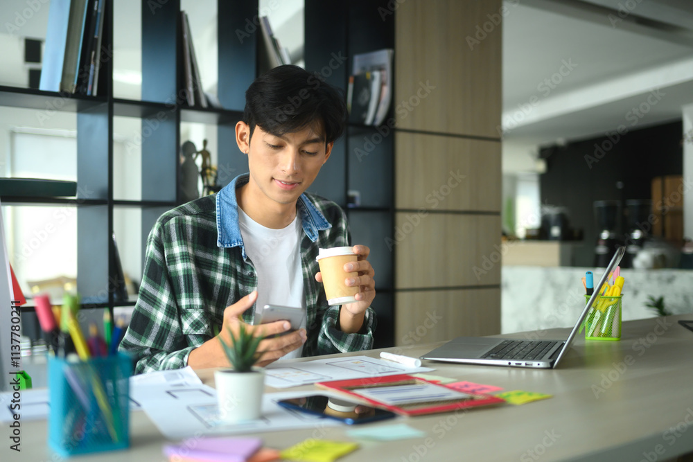 Aufkleber designer holding smartphone working on new mobile application interface design at desk