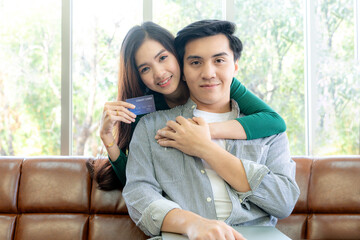 A young couple shopping online together at home using a credit card