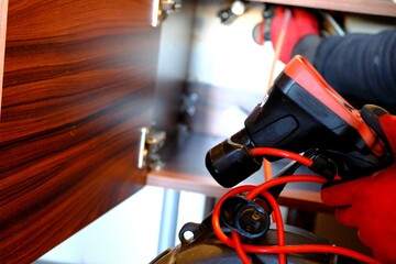 A plumber is trying to open a clogged bathroom pipe using a camera system. Close-up view of opening...
