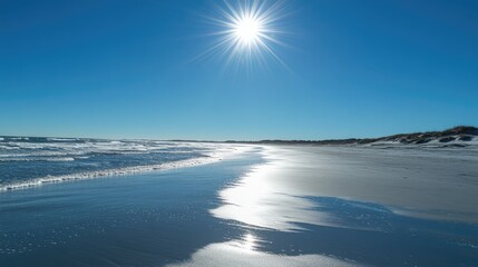 Obraz premium A clear and bright midday sky with the sun shining brightly over a sandy beach and turquoise waves.