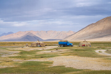 Scenic summer landscape view of traditional yurts and soviet era blue truck in high altitude...