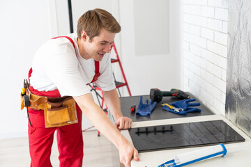 craftsman installs hob in kitchen. Household Appliance Installation Services Concept