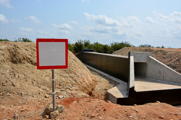Red-Framed Blank Sign in Front of an Under-Construction Culvert