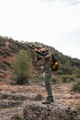 Obraz premium Hunter standing on rock aiming with rifle in forest