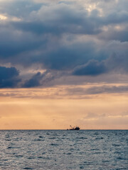 Fototapeta premium Fishing boat at dramatic sunset on Black Sea coast