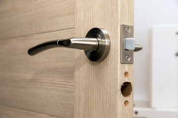 Installation of a new door handle on wooden door, closeup.