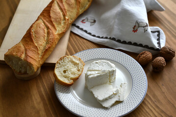 Fresh cheese, french bread and walnuts on a wooden table