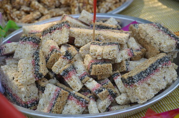 Thai dessert for local wedding ceremony, platter filled with square pieces of a layered dessert made from rice and bean