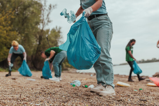 Volunteers collecting garbage on river bank wearing gloves - Powered by Adobe