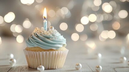 Elegant Blue Cupcake with Lit Candle and Pearl Decorations on Bokeh Background