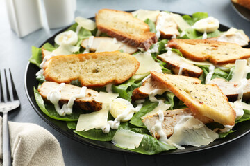 Delicious Caesar salad with chicken on grey textured table, closeup