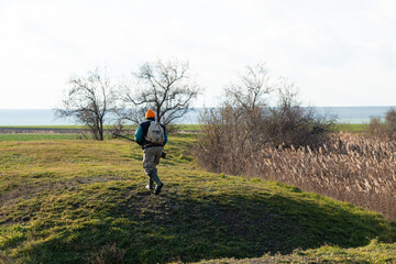 Mature hunter man holding a shotgun and walking through a field